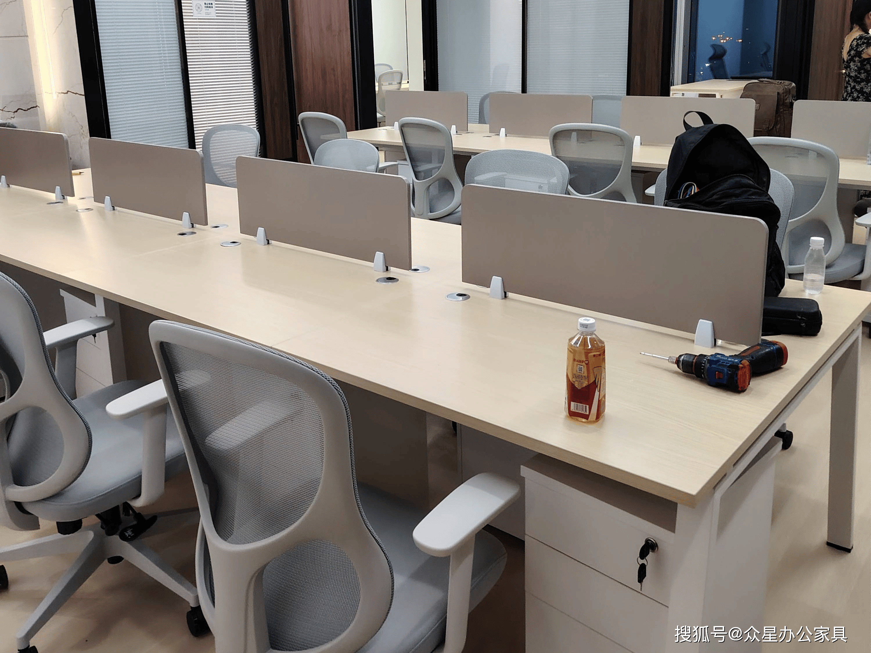 员工坐在开放式办公的工位前工作,桌面整洁光线明亮